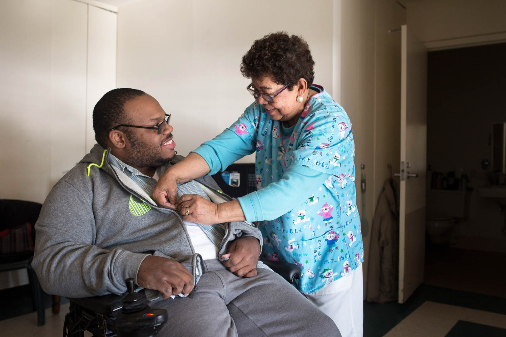 CHCA caregiver Cecilia helps client client Sam button his shirt