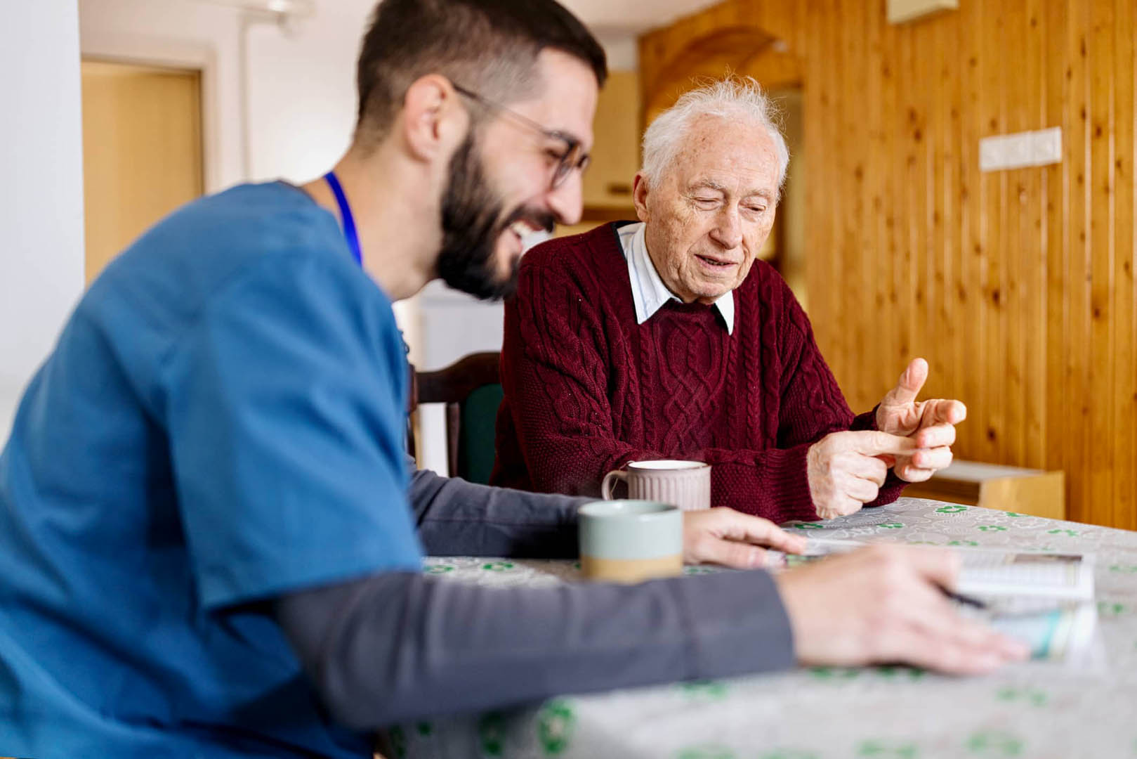Caregiver and client sit at a kitchen table and at a newspaper